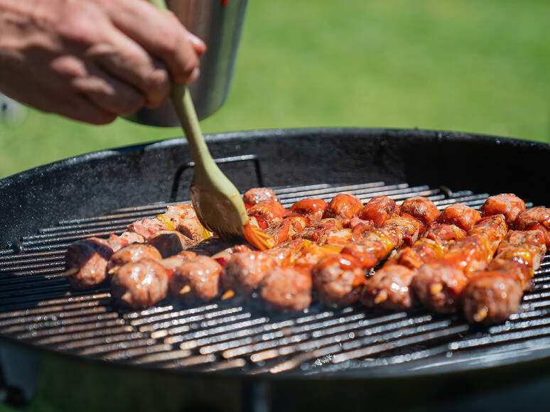 Spiedini misti di carne e verdure con salsa BBQ sfrigolano sulla griglia rovente per un catering a Trento.