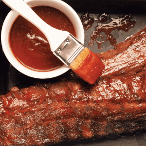 Costine di carne succulente spennellate con abbondante salsa BBQ, preparate per un evento di catering a Trento.