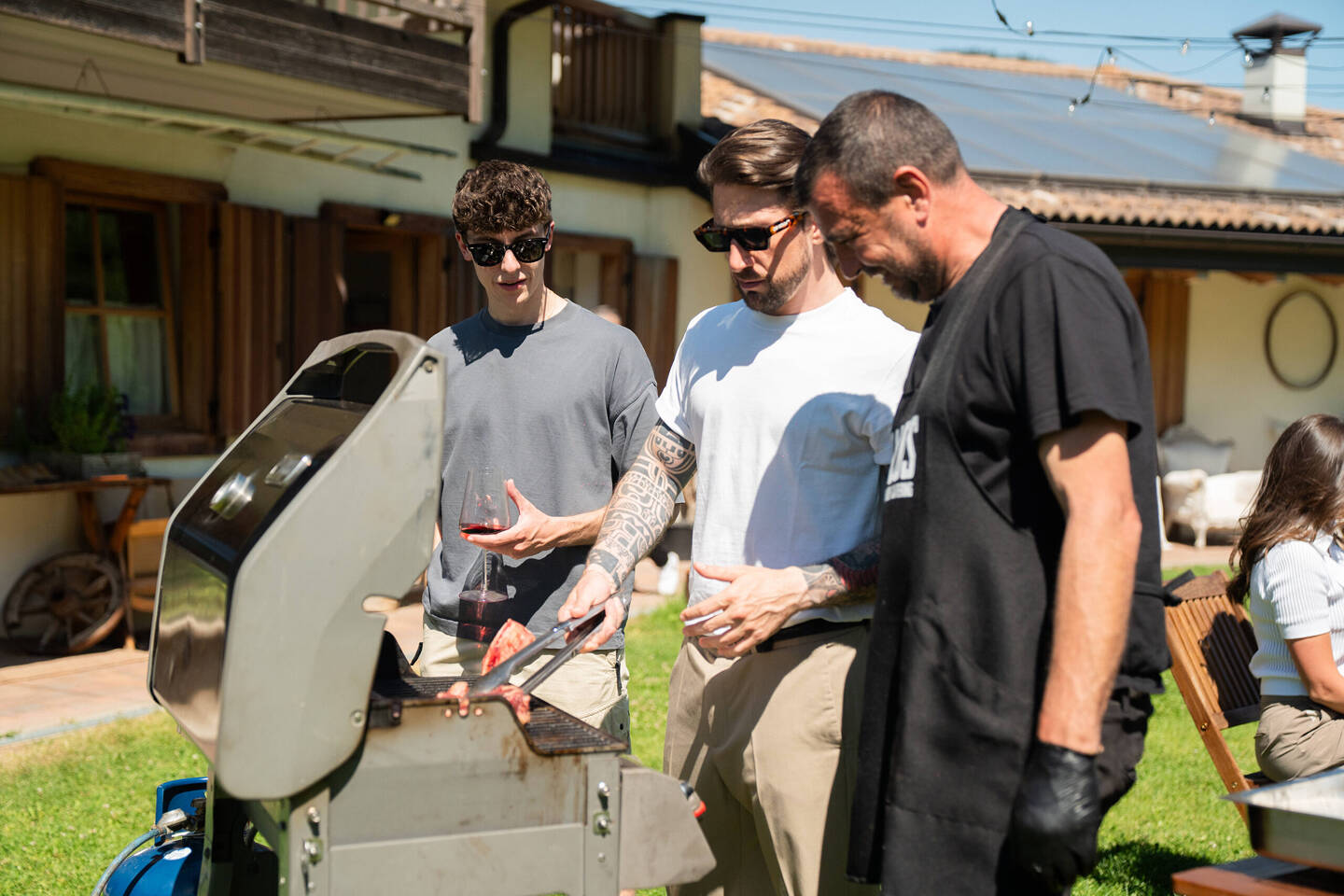 struttore e partecipanti durante un corso pratico di BBQ all'aperto a Trento, concentrati sulla cottura della carne alla griglia.