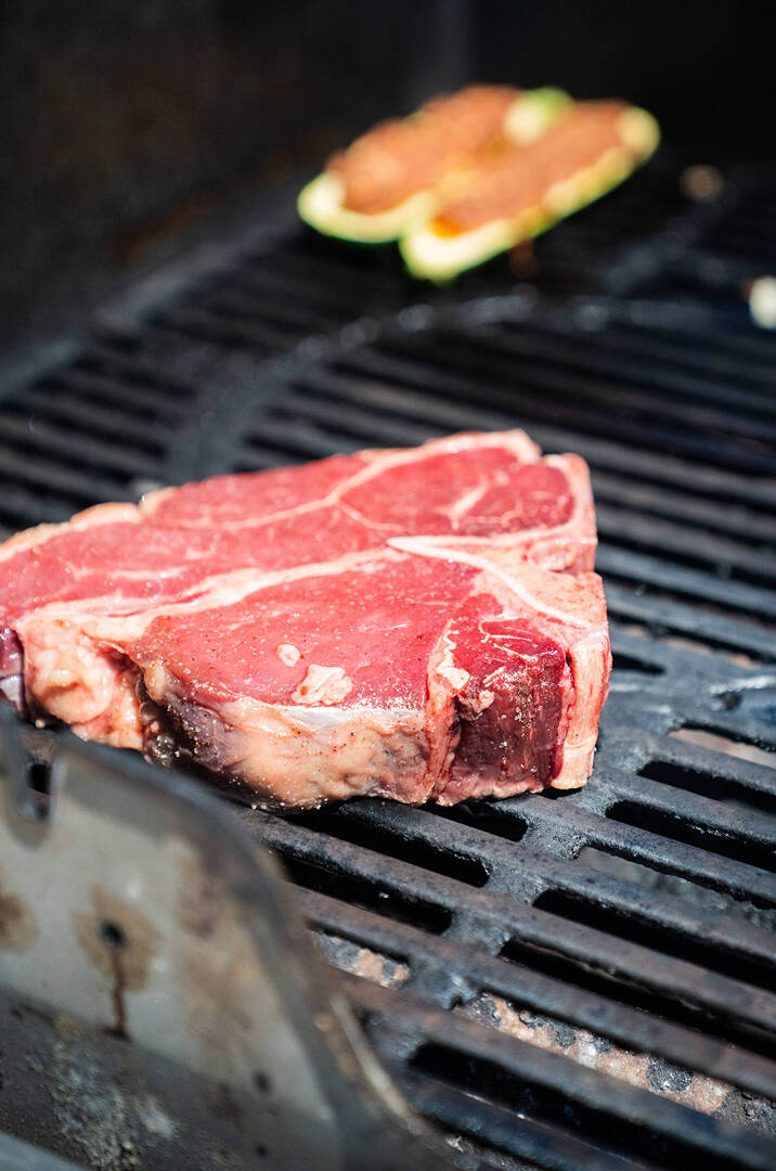 Una bistecca T-bone di carne pregiata in cottura su una griglia per barbeque rovente.